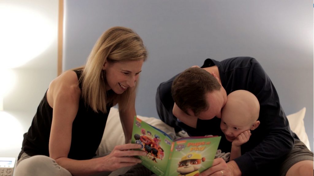 Mother and father reading with their son in one of the Ronald McDonald House bedrooms