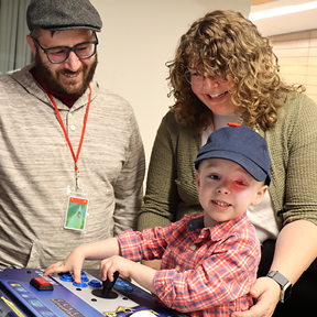 The Devaney Family-Mother and Father watching their son play an arcade game at the Ronald McDonald House