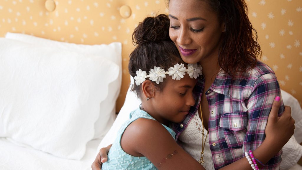 Mom holding her daughter in a bed