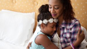 Mom holding her daughter in a bed