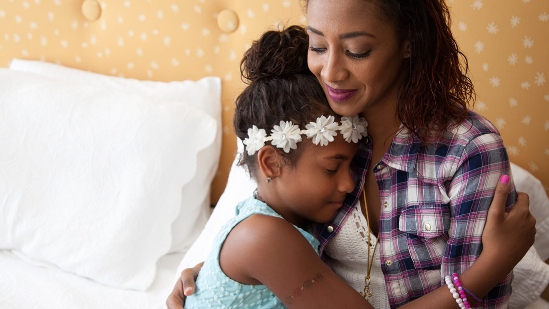 Mom holding her daughter in a bed