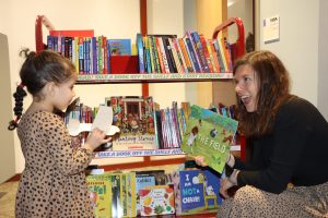 RMHC employee showing a book to a child who is visiting the family room