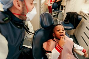 A child points at his tooth while dentist watches