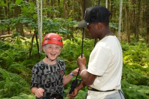 Staff assisting a camper on the zip line course