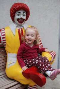 Girl sitting on Ronald McDonald statue